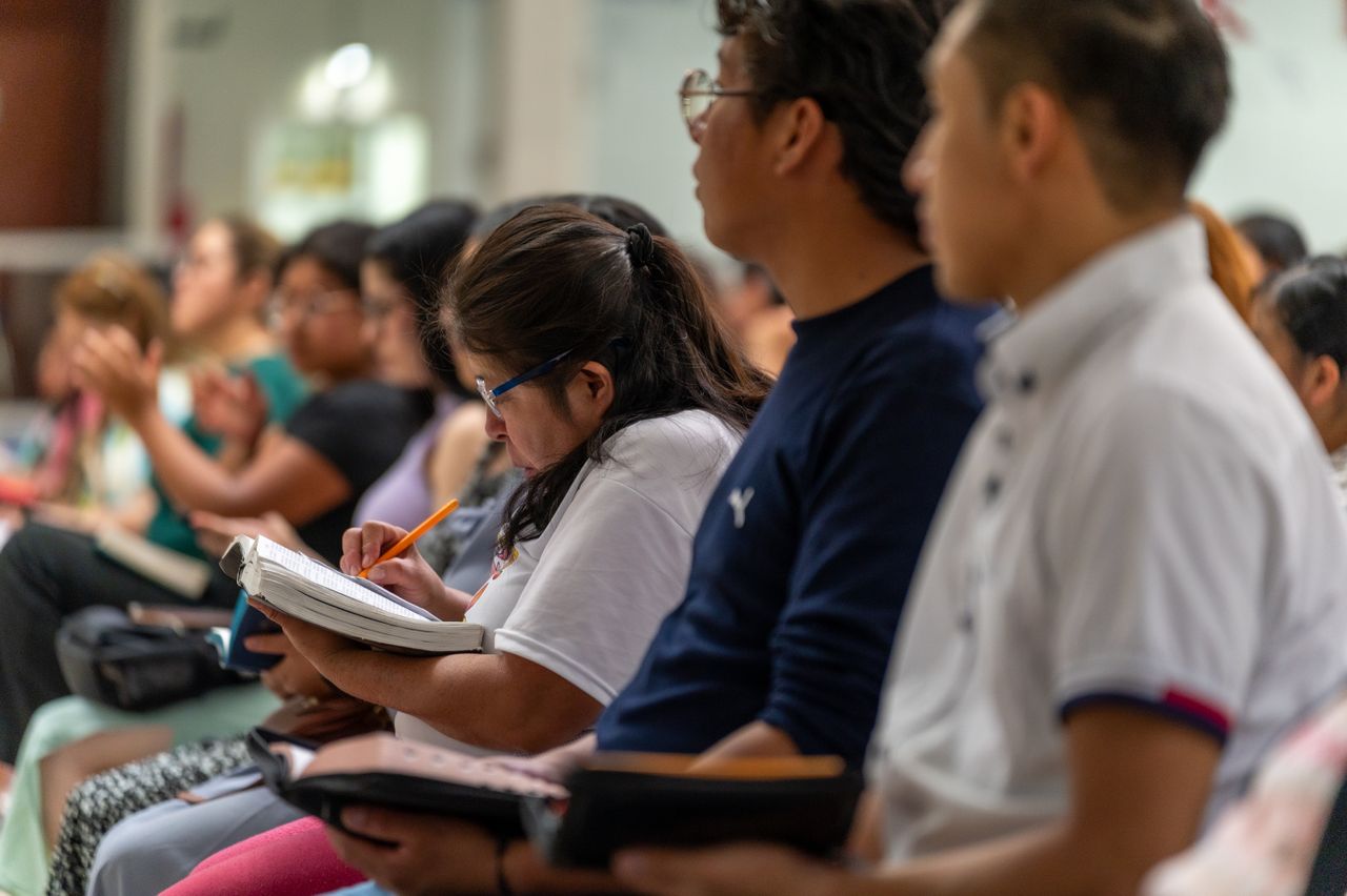 creative-02 Adults sitting in a religious gathering, engaged in note-taking and worship in Mexico.