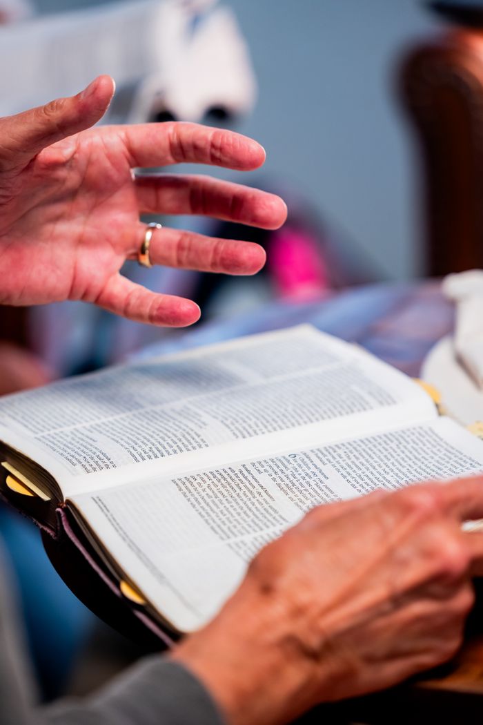 our-story Close-up of hands engaged in Bible study at an indoor setting, promoting spiritual discussion.