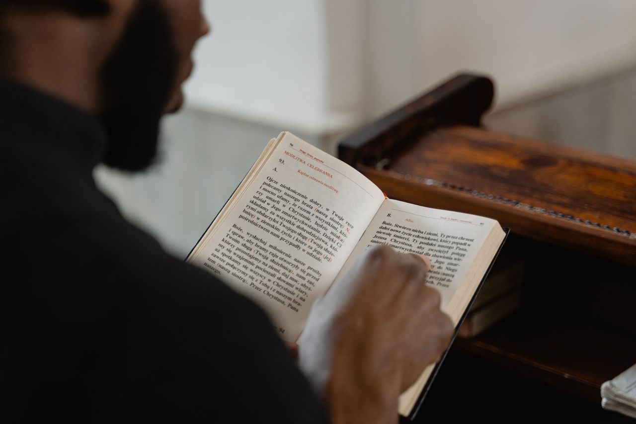 brand-03 A man reading a religious book inside a church, focusing on a spiritual moment.