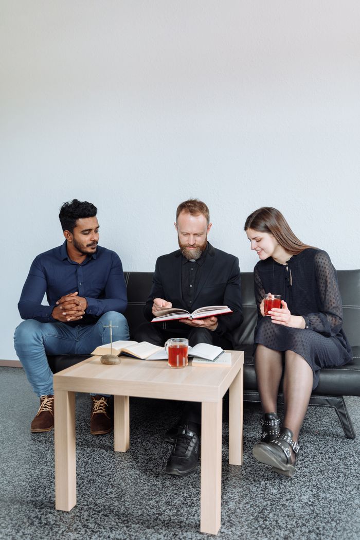 The Art of Drawing Readers In: Your attractive post title goes here Three adults sitting indoors discussing religious text with open books and drinks.