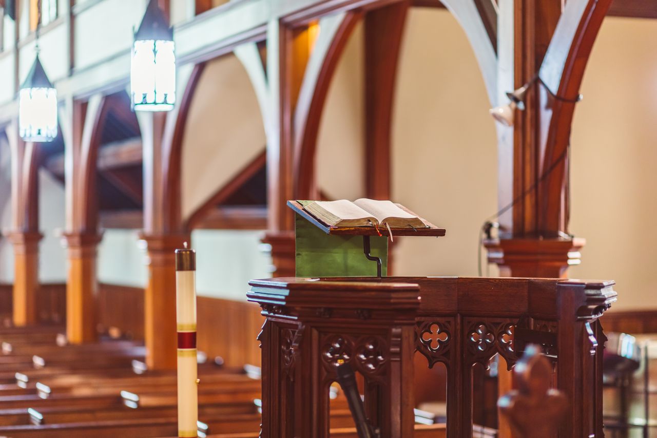 mobile-01 A wooden pulpit with an open Bible in an empty church setting.